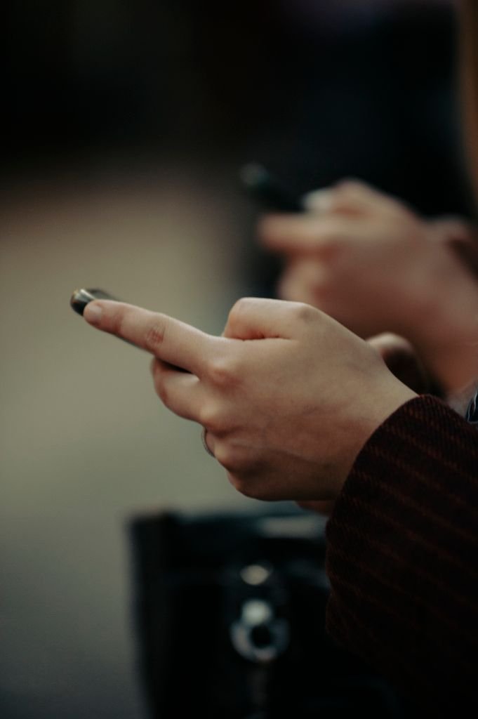 Detailed photo of hands holding smartphones outdoors, showcasing modern technology in use.
